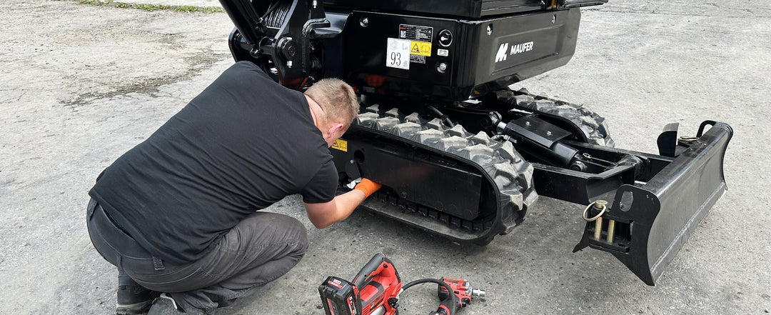 Serwisant sprawdza ilość oleju w rolkach w gąsienicy