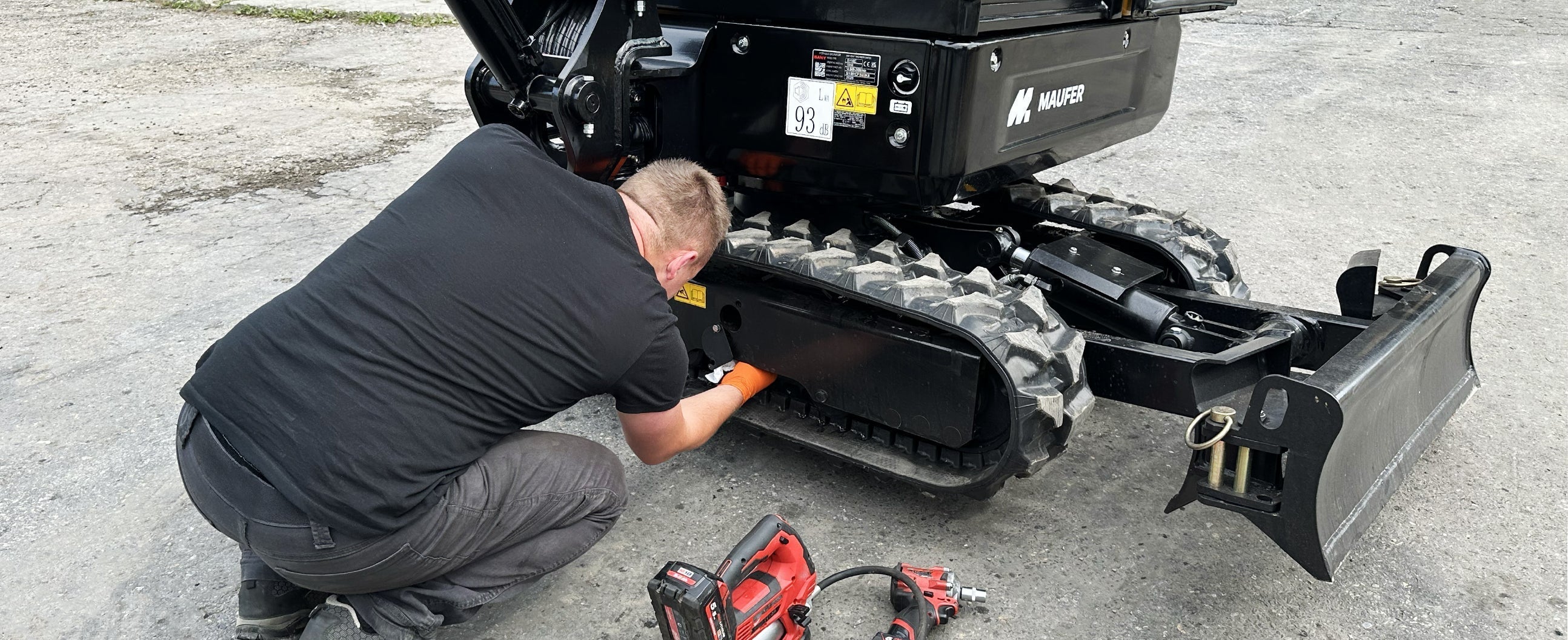 Serwisant sprawdza ilość oleju w rolkach w gąsienicy