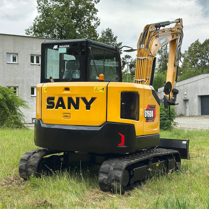 Koparka gąsienicowa SANY SY60U w żółto-czarnej kolorystyce, widok z tyłu na kabinę operatora i ramię robocze, maszyna stoi na trawie.