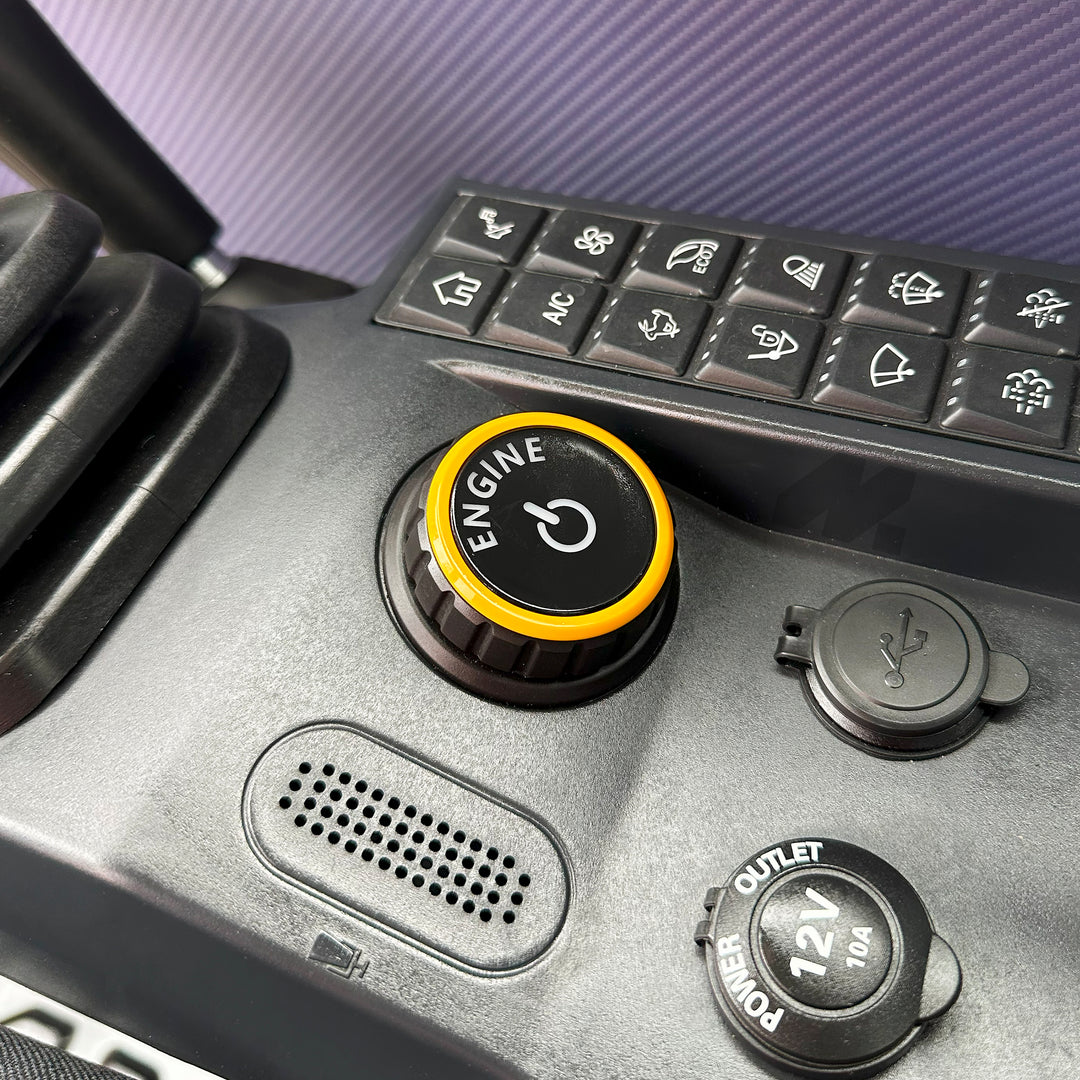 Przycisk start-stop silnika koparki SANY SY60U z żółtą obwódką, obok panel z ikonami funkcji oraz gniazdo zasilania 12V i port USB.