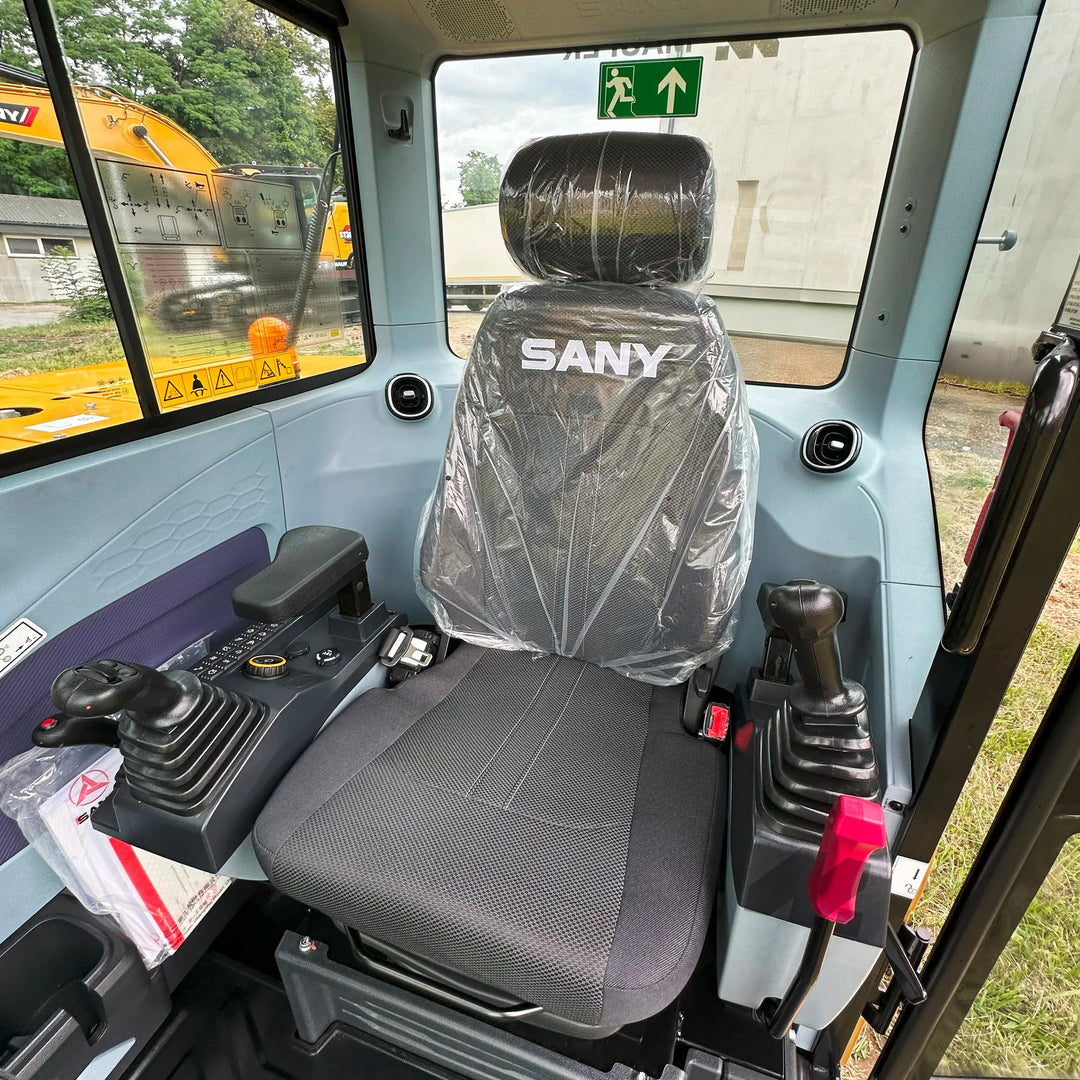Kabina operatora koparki SANY SY60U z ergonomicznym fotelem, podłokietnikami oraz joystickami sterującymi po obu stronach stanowiska.