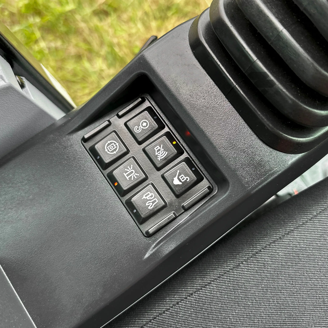 Panel przycisków funkcyjnych w kabinie koparki SANY SY60U, z ikonami sterowania światłami, ogrzewaniem siedzenia, wycieraczkami i dodatkowymi systemami.
