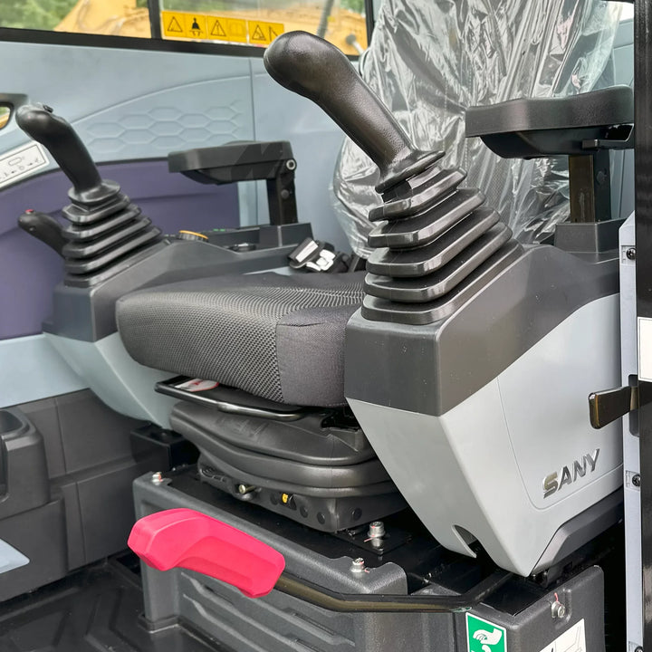 Fotel operatora koparki SANY SY60U z ergonomicznymi joystickami sterującymi po obu stronach oraz dźwignią bezpieczeństwa w czerwonym kolorze.