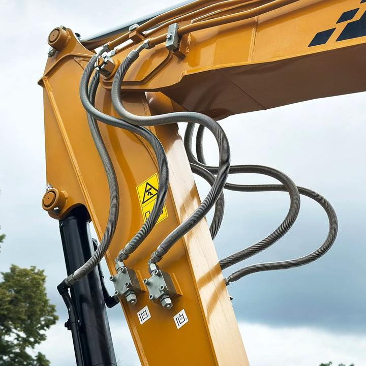 Przewody hydrauliczne i elementy instalacji ramienia roboczego koparki SANY SY60U, widok zbliżony na mocowania i oznaczenia bezpieczeństwa.