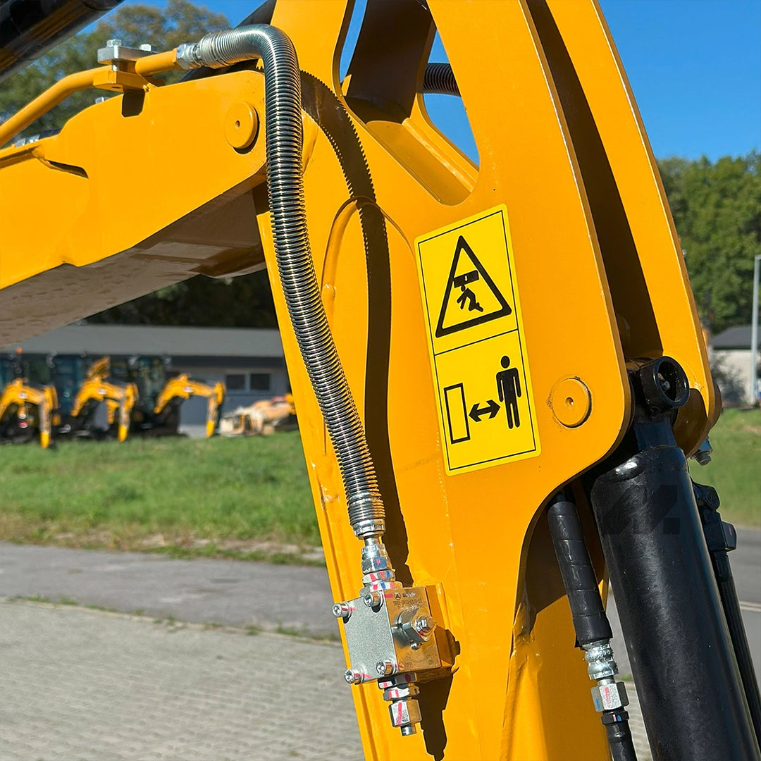Ramię minikoparki Sany SY18C z widoczną linią hydrauliczną AUX w oplocie stalowym i naklejkami ostrzegawczymi