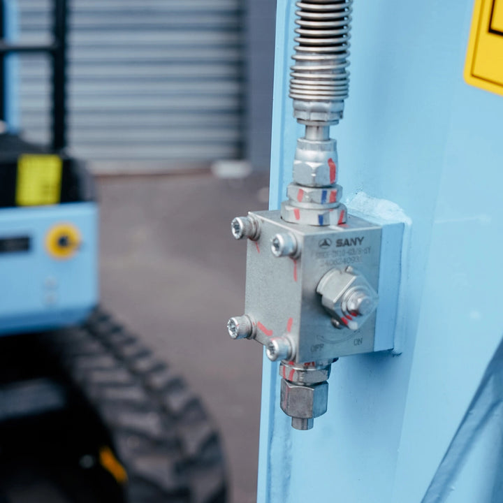 Zbliżenie na zawór hydrauliczny i przyłącza pomocnicze (AUX) w minikoparce elektrycznej Sany SY19E.