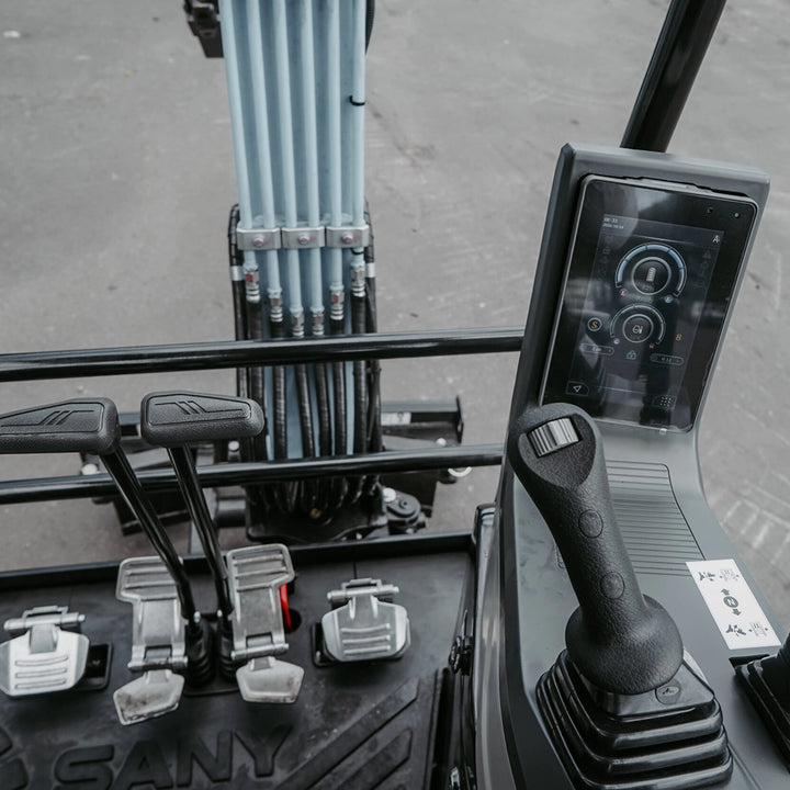 Cyfrowy wyświetlacz, joystick i pedały sterowania w elektrycznej minikoparce SANY SY19E