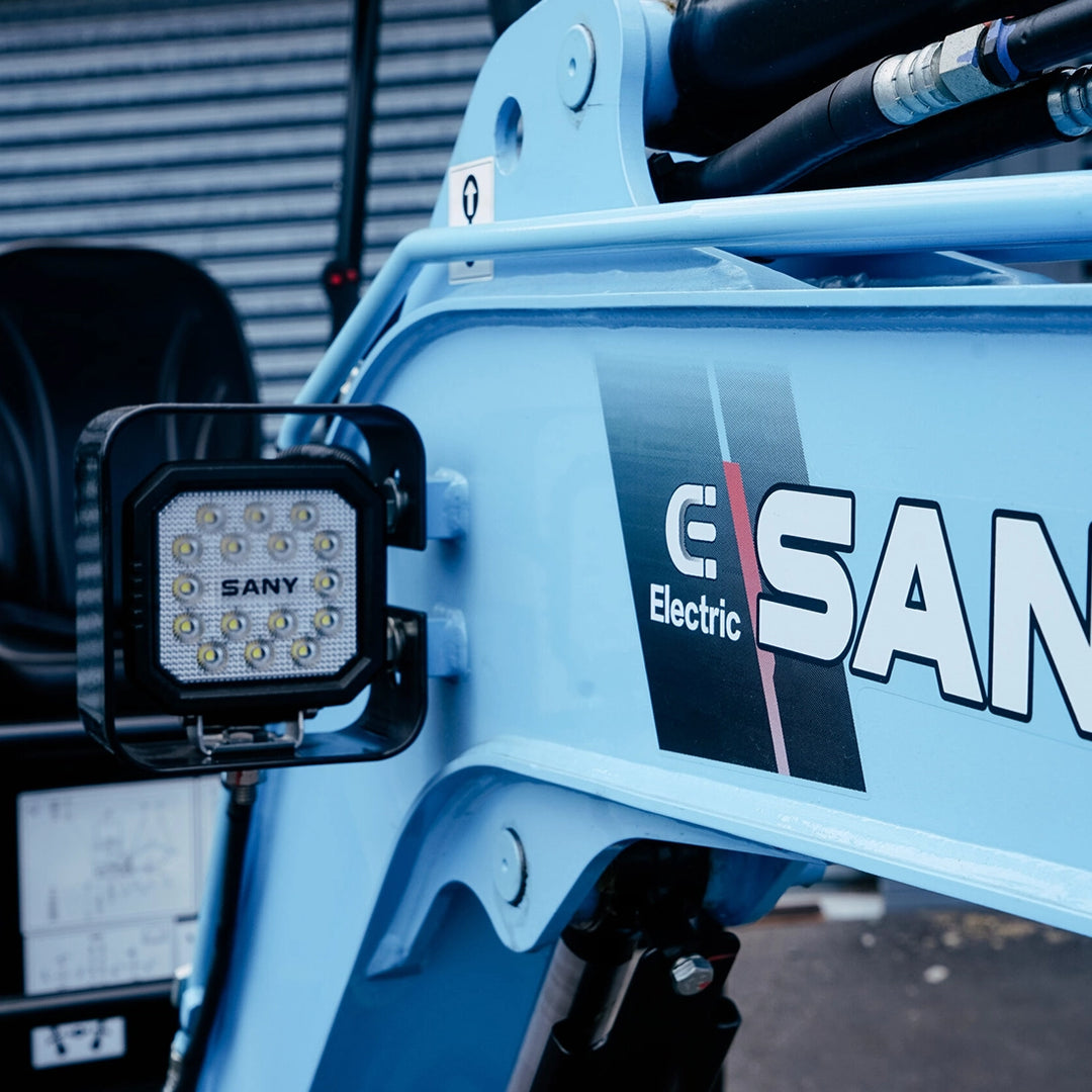 Reflektor LED i logo Sany Electric na niebieskim ramieniu minikoparki Sany SY19E.