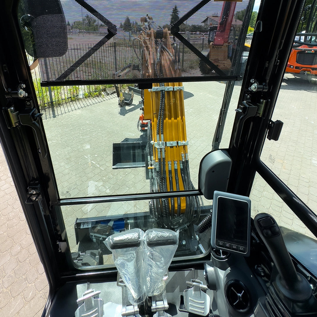Wnętrze kabiny koparki do 3 t Sany SY26C - widok z fotela operatora na dżojstiki, pedały i wyświetlacz LCD.