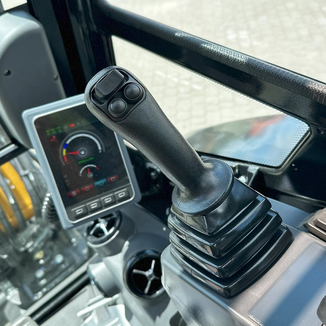 Zbliżenie na dżojstik z przyciskami sterującymi oraz monitor pokładowy wyświetlający parametry pracy Sany SY26C.