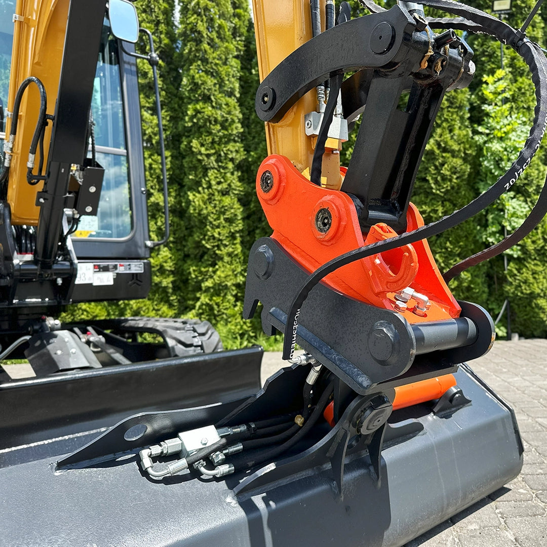 Szybkozłącze mechaniczne minikoparki Sany SY26C zamontowane na ramieniu, widoczne nad lemieszem maszyny.