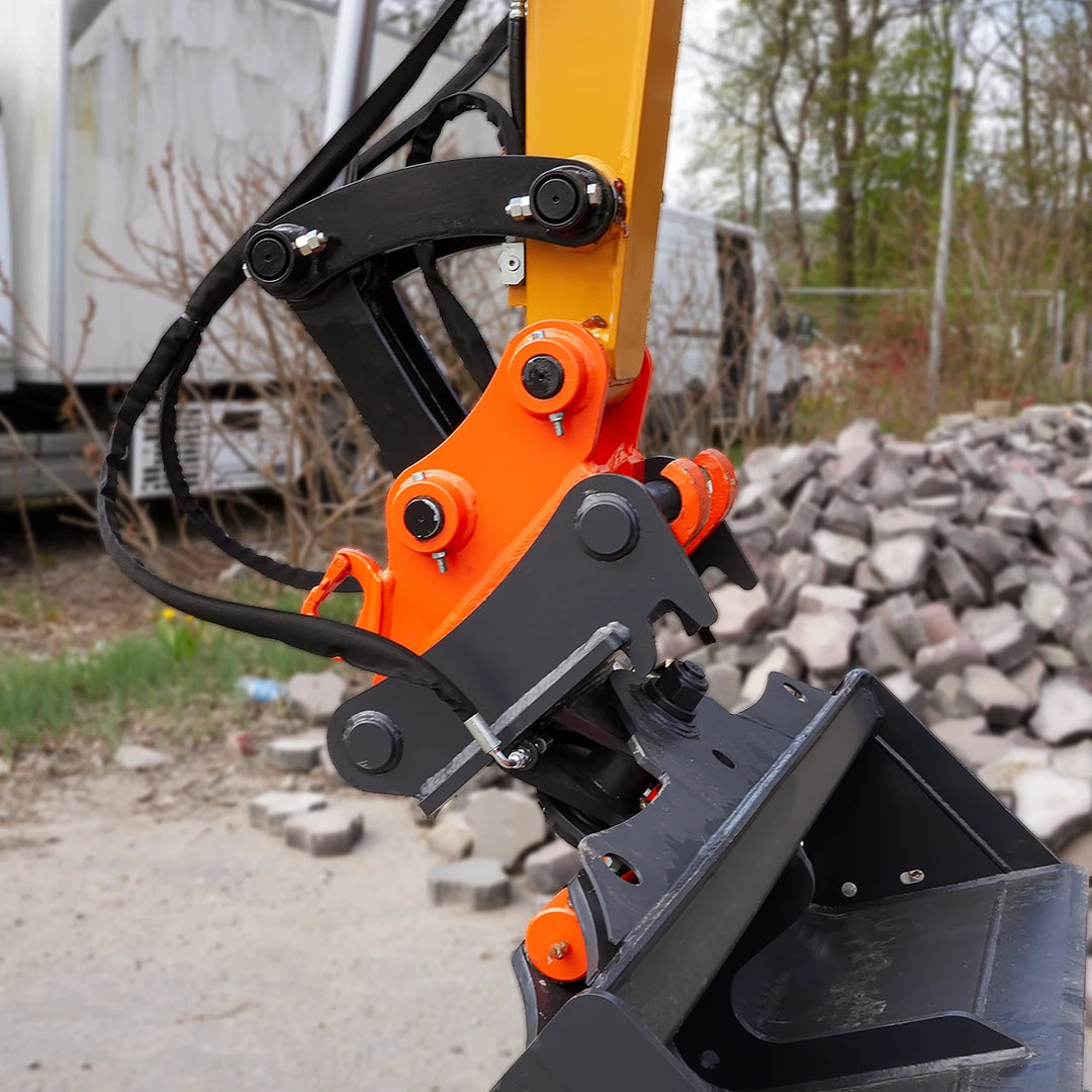Zbliżenie na szybkozłącze hydrauliczne i mocowanie łyżki w minikoparce Sany SY26U - solidne sworznie i detale układu hydraulicznego ramienia.