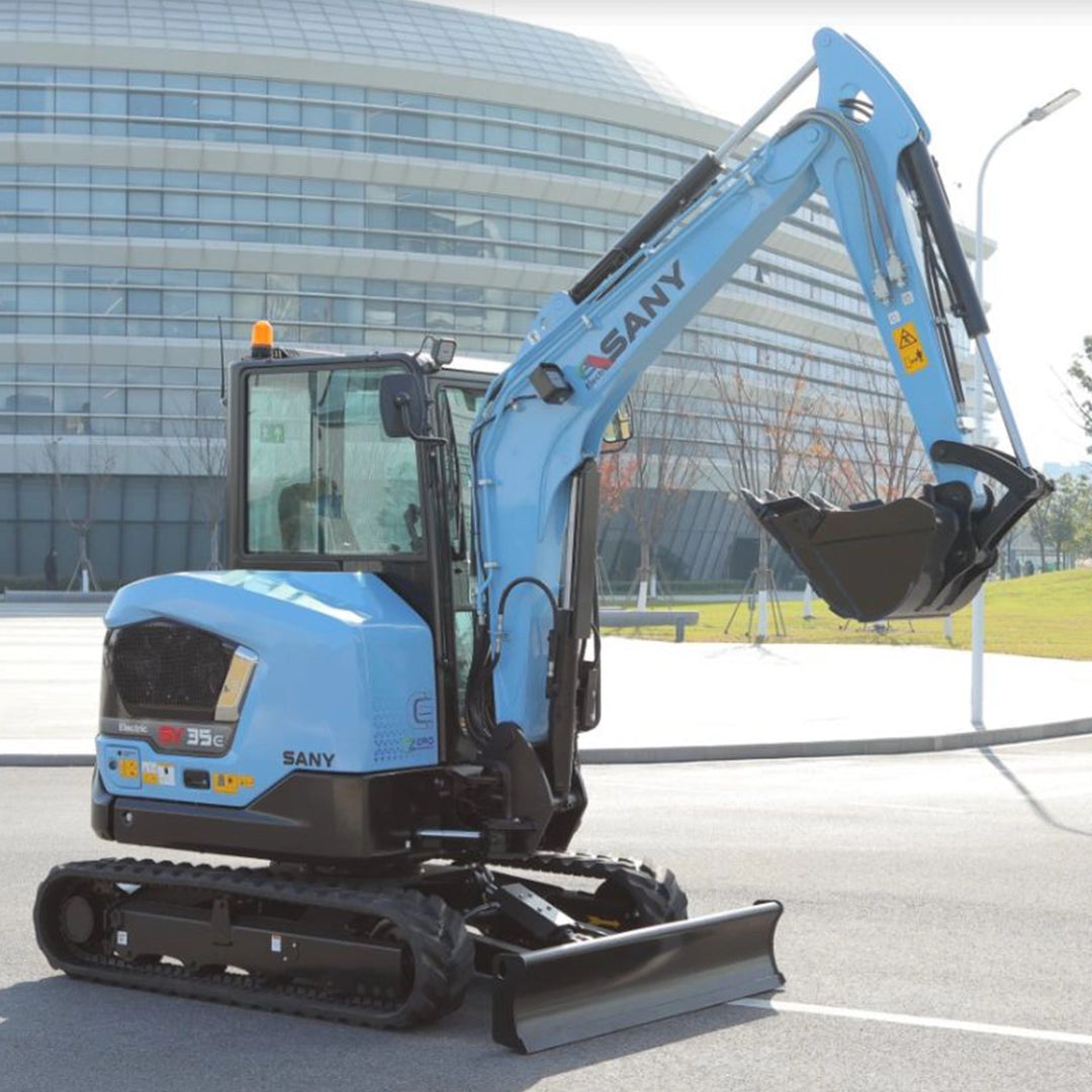Mini-koparka elektryczna Sany SY35E z uniesionym ramieniem i opuszczonym lemieszem na tle biurowca.