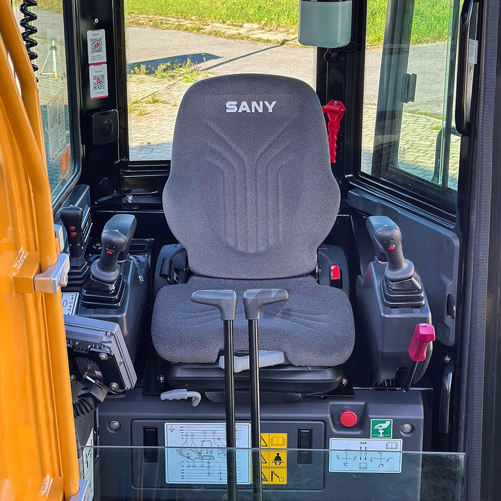 Ergonomiczne wnętrze kabiny Sany SY35U - komfortowy fotel, precyzyjne joysticki sterujące i czerwona dźwignia blokady bezpieczeństwa.