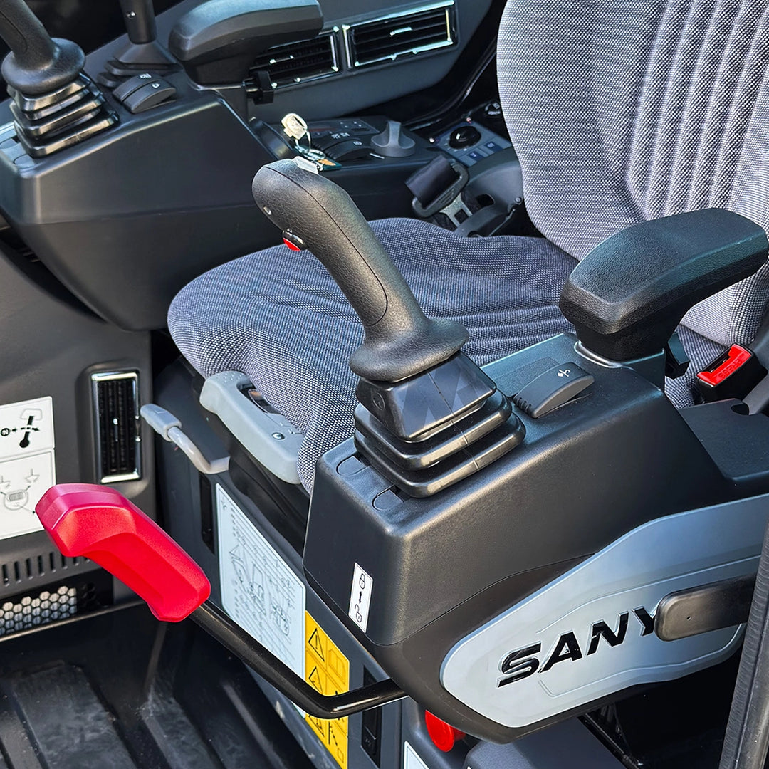 Wnętrze kabiny Sany SY35U: detal joysticka hydraulicznego, dźwignia blokady bezpieczeństwa oraz komfortowe siedzisko operatora.