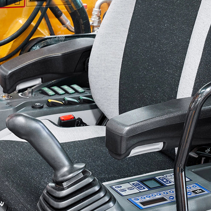 Wnętrze kabiny koparki Sany SY80U, ergonomiczny fotel z podłokietnikami, precyzyjne joysticki sterujące oraz panel przycisków funkcyjnych.